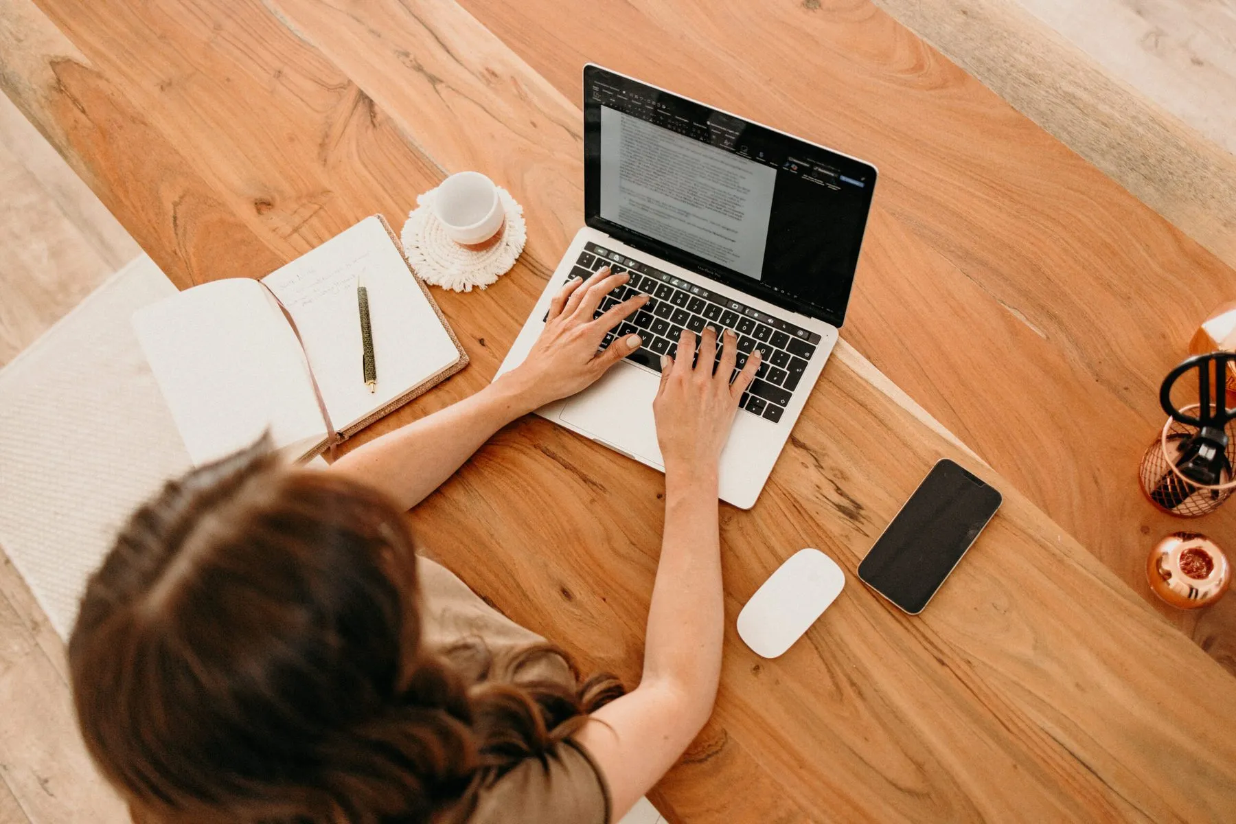 Nina Grimm arbeitet am Laptop an einem Holztisch